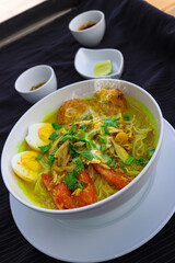 INDONESIAN CULINARY CHICKEN SOUP NOODLE WITH SLICE BOILING EGG AND FRIED MASHED POTATOS AS TOPPING