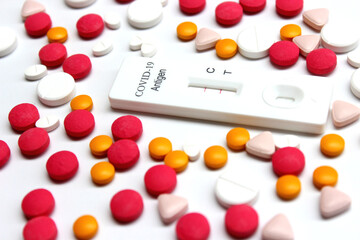 Positive test result of Covid-19 antigen test kit and drug tablets on the white background