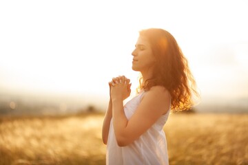 Young person praying against sky. Spirituality, religion, meditation, christianity prayer.