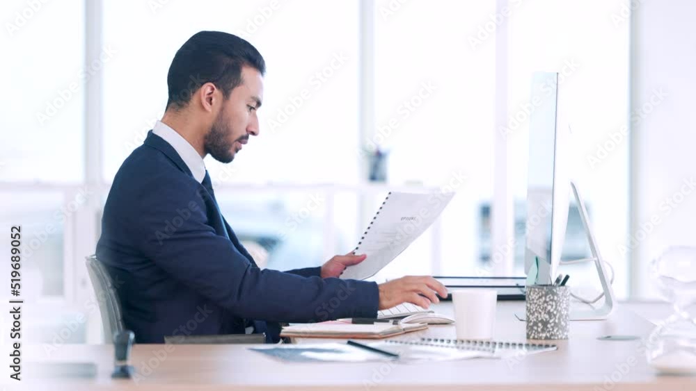Poster Serious, thinking businessman analyzing information and thinking of ideas to be innovative for his next project. Data analyst reading paperwork sitting behind his computer in his office.