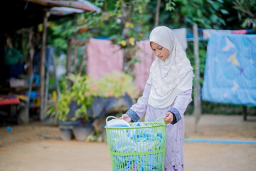 Islamic girls put clothes to dry in a basket.

