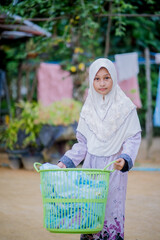 Islamic girls put clothes to dry in a basket.
