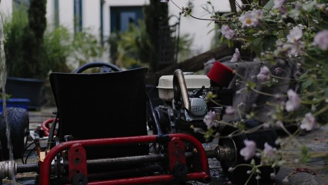 Cinematic shot of mechanic washing the rear axle of a DIY go-kart in the backyard