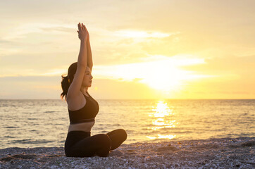 Young healthy woman practicing yoga on the beach at sunset. Beach at Chonburi, Thailand.