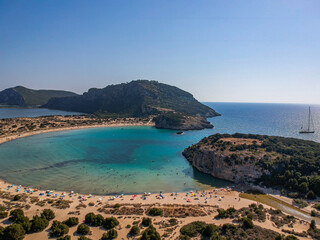 Aerial view of the famous semicircular sandy beach and lagoon of Voidokilia, Greece overcrowded during high tourist season