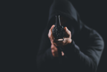 Criminal holding machine gun pointing gun to target in front on dark background,selective focus on...