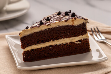 Japanese mini whipped cream chocolate cake served on a beige-white square plate for a coffee break time. 