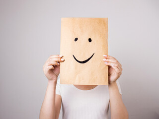 woman holding paper with a painted smile in front of her face - obrazy, fototapety, plakaty