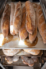 Finished French bread in the bakery on the racks. Baguettes, rustic bread, crown of kings Bordeaux. Vertical photo.