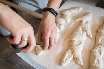 The process of making French traditional bread. Baguettes ear, notching the dough. Front view.