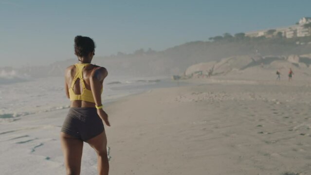Active, fit and sporty woman running, sprinting or jogging on the seashore at the beach. One focused, serious and determined black female training, doing cardio and exercising in nature during summer