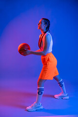 a girl with a basketball in orange shorts, a t-shirt and a baseball cap. sportswoman in golfs and sneakers on a blue background. Physical education teacher. basketball player