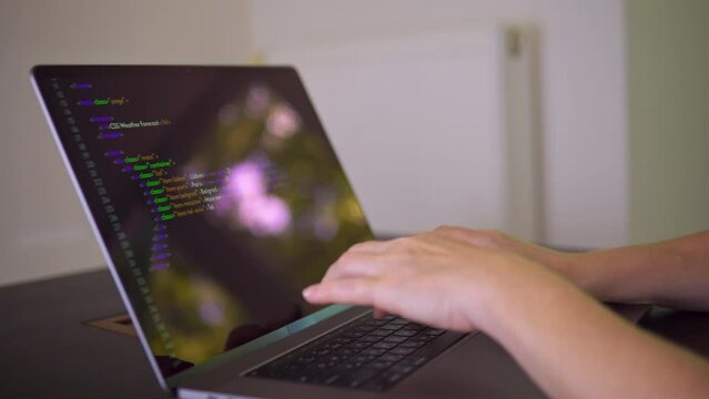 A programmer is writing program code on the laptop.