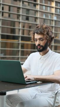 Stylish businessman with makeup working with laptop in an outdoor coffee shop at financial district. Circular camera movement. lgbti concept.