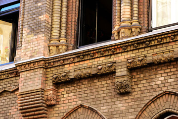 ornate yellow brick exterior facade detail and closeup. arched window and corbeled brick sill. decorative elements. old european architecture. urban street. brick corbel feature. travel and tourism. © Istvan