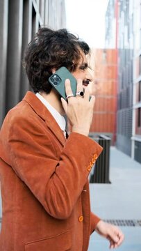Stylish businessman talking on the phone while walking in financial district. lgbti concept.