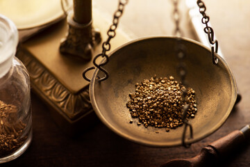 Commerce, trade profit, and exchange. Weighing a gold nugget on a old brass scale dish for trading....