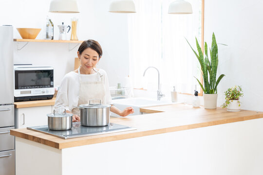 キッチンで料理をする笑顔のミドル女性（家事・主婦・自炊）