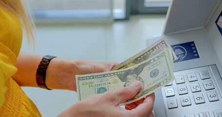 Woman counting us dollars near ATM machine 