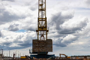 Tower crane close-up against the background of the cloudy sky. Modern building technologies.