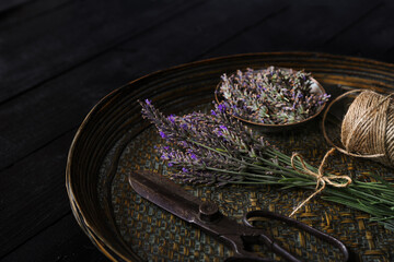 Harvested fresh lavender with scissors and jute twine roll in a bamboo tray in moody tone