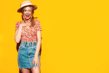 Portrait of young beautiful smiling blond female in trendy summer clothes. carefree woman posing near yellow wall in studio. Positive model having fun indoors. Cheerful and happy. In hat