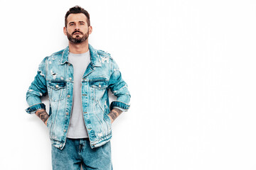 Portrait of handsome confident stylish hipster lambersexual model. Sexy man dressed in jeans jacket. Fashion male isolated on white wall in studio