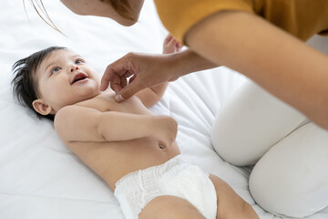 mother changing diaper a newborn baby lying on the bed