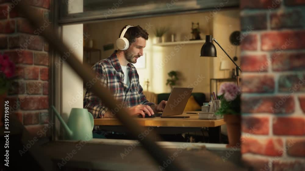 Poster handsome caucasian man working on laptop computer while sitting behind his desk at home office. free