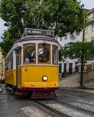 Plakat Yellow tram no. 28 on one of Lisbon's stone streets. Portugal