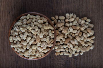 Bowl full of dried mulberry on a wooden background
