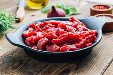 Raw uncooked beef meat sliced in strips with Ingredients for beef stroganoff over rustic wooden background.