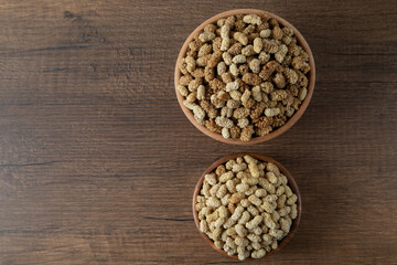 Bowl full of dried mulberry on a wooden background
