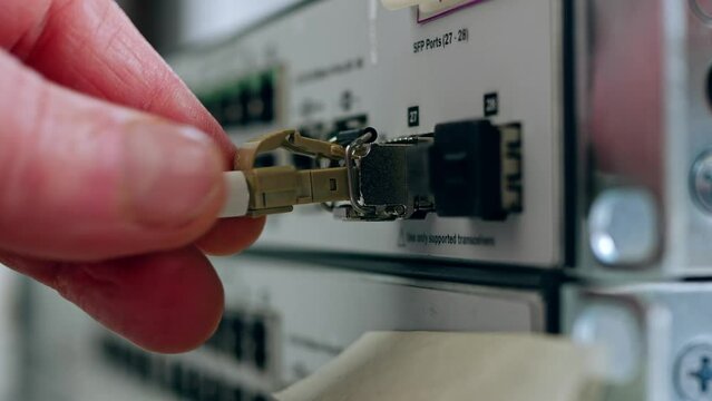 Network engineer connects fiber cable on computer switch