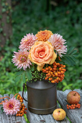 Arrangement mit Blumenstrauß mit orange Rose, Dahlien und Ebereschen-Beeren in vintage Milchkanne