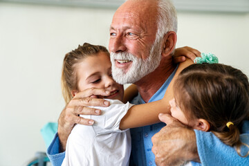 Happy grandfather and his grandchildren laughing and enjoying leisure time together.