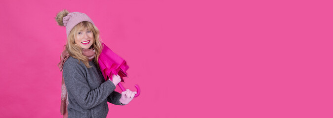Fototapeta premium mature smiling woman with umbrella on pink background