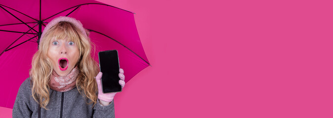 woman with surprised expression and umbrella showing mobile phone