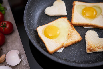 Fried egg Toasts with heart shaped holes on frying pan