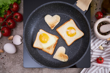 Fried egg Toasts with heart shaped holes on frying pan