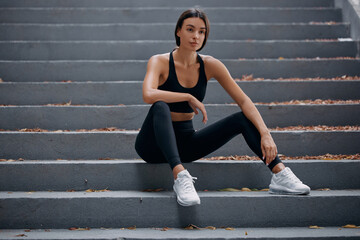Fototapeta na wymiar Woman sitting on the stairs outdoors, resting after nice workout session