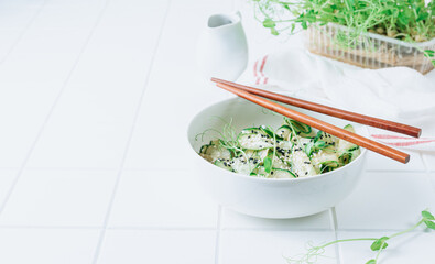 Salad of sliced cucumbers with herbs and sesame seeds in a white bowl