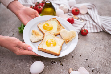 Woman pits plate with Fried Egg on Toast Bread on concrete table for Breakfast