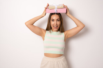 Amazed young brunette woman holding gifts standing isolated over white background.