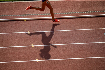 陸上競技場で走る女子選手の影