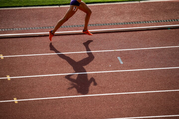 陸上競技場で走る女子選手の影