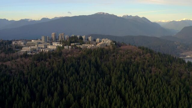 Scenic SFU On Rich Vegetation Of Burnaby Mountain Overlooking Distant Majestic Ranges- Burnaby, Canada. Wide Drone Shot