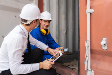 Dock manager and engineer worker in safety helmet sitting in front of container in shipping yard and discuss. Import and export product. Manufacturing transportation and global business concept.