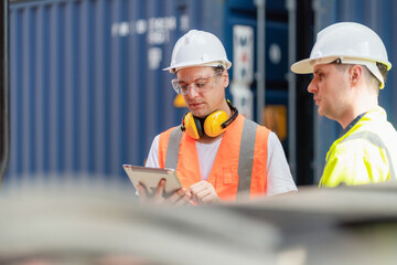 Dock manager and engineer worker in safety helmet discuss at the container in shipping yard with...