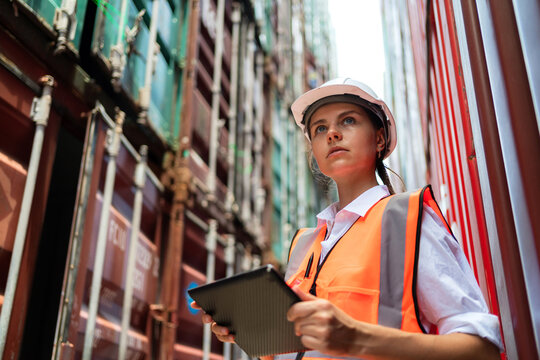 Dock manager or engineer worker in casual shirt with vest standing in shipping container yard holding tablet. Import and export product. Manufacturing transportation and global business concept